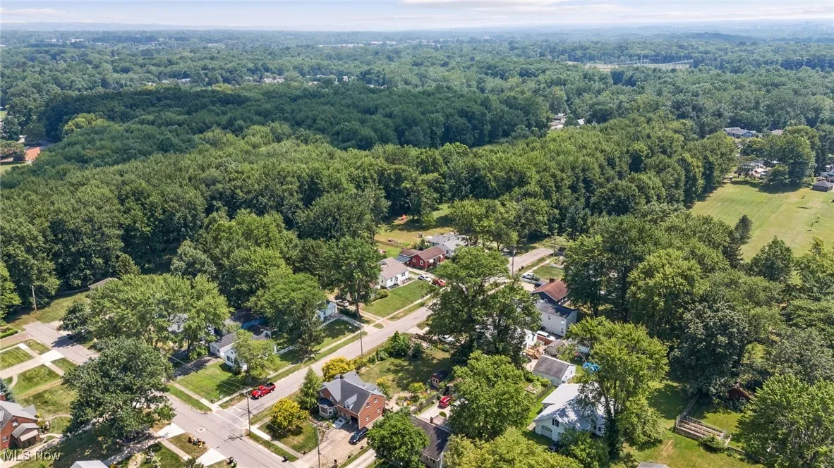Aerial view of property and surrounding area with a heavily wooded area