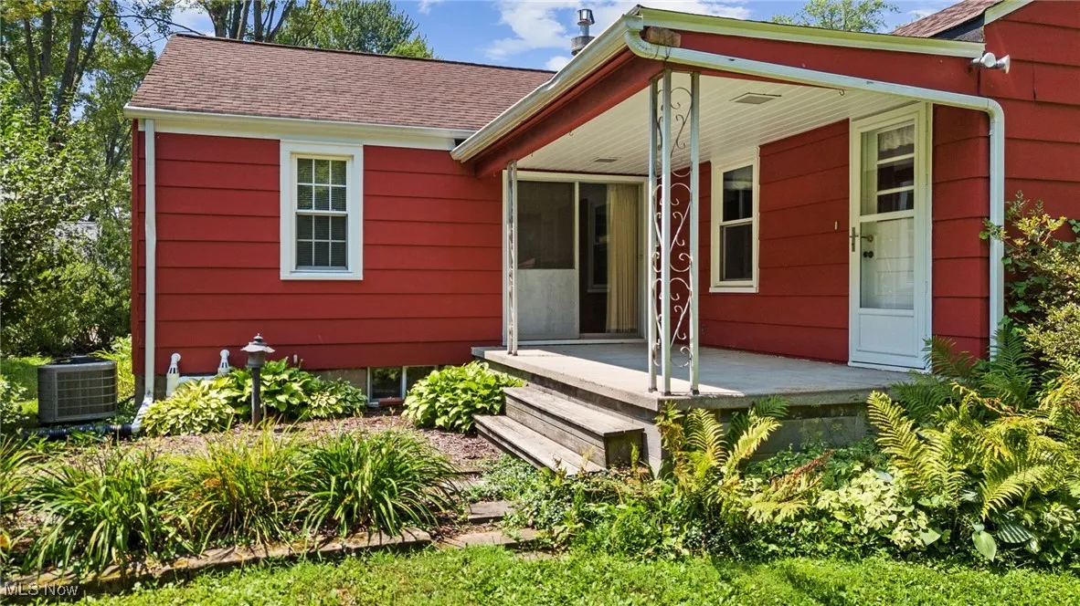 Rear view of property with a shingled roof and a porch