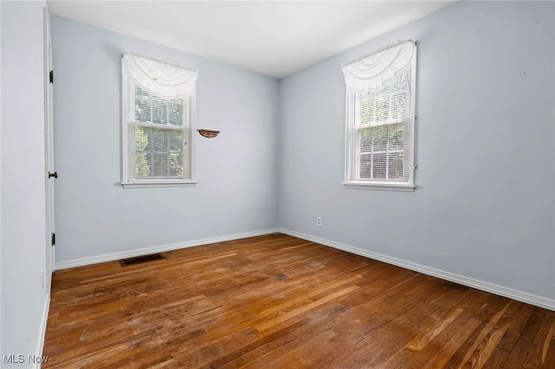 Unfurnished room featuring hardwood / wood-style floors and baseboards