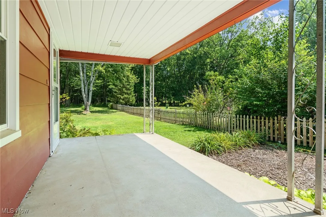Fenced backyard featuring a patio area and view of wooded area