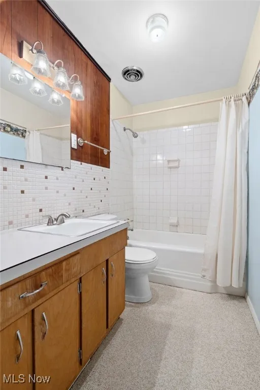 Full bath with vanity, shower / bathtub combination with curtain, and tasteful backsplash