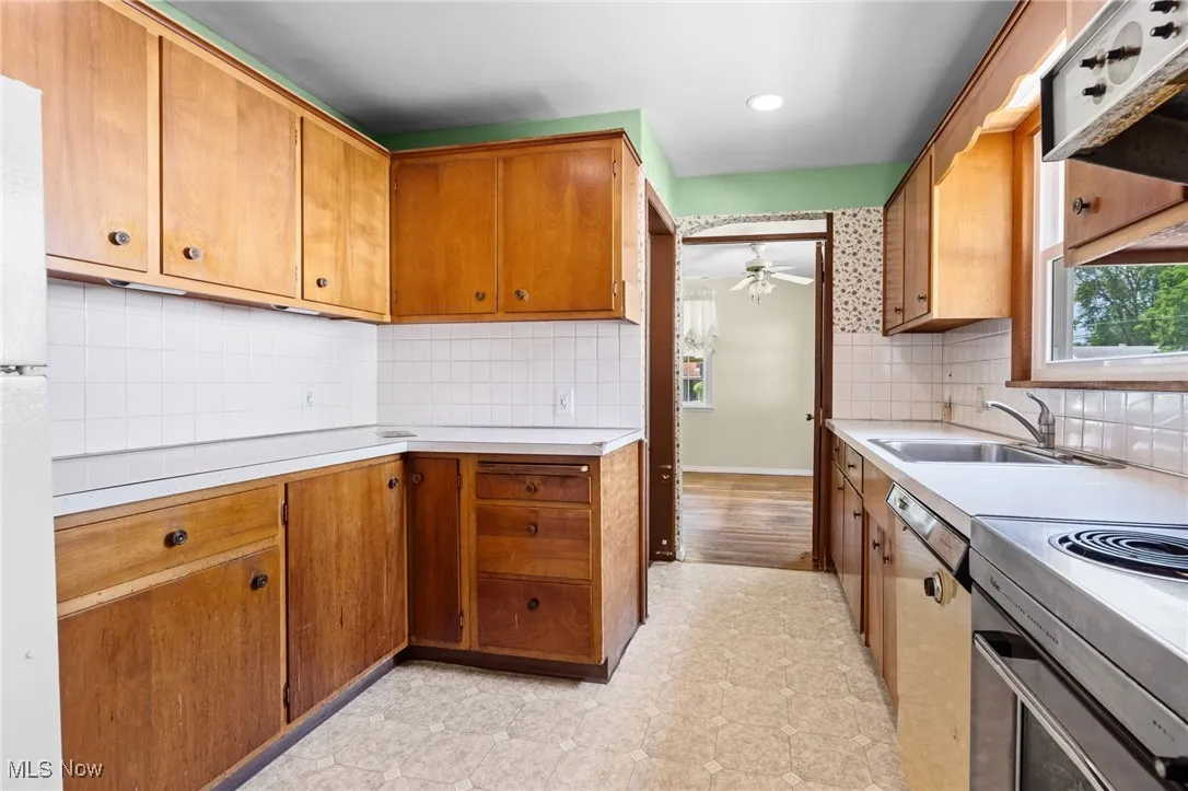 Kitchen with a ceiling fan, light countertops, tasteful backsplash, and light flooring