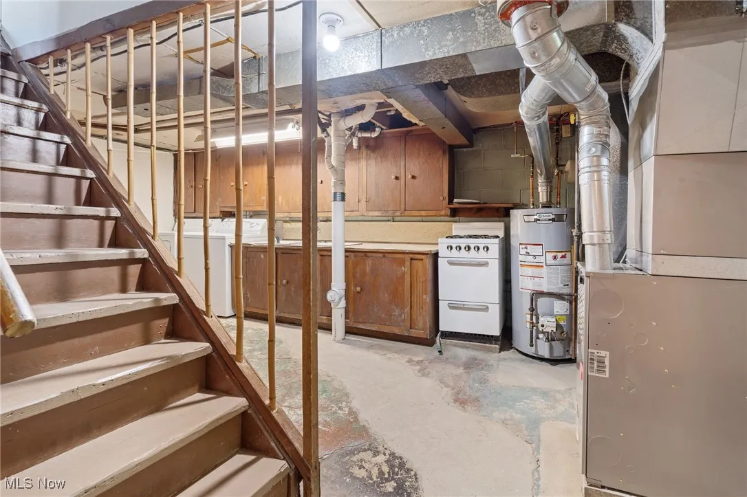 Unfinished basement with heating unit, water heater, and stairway