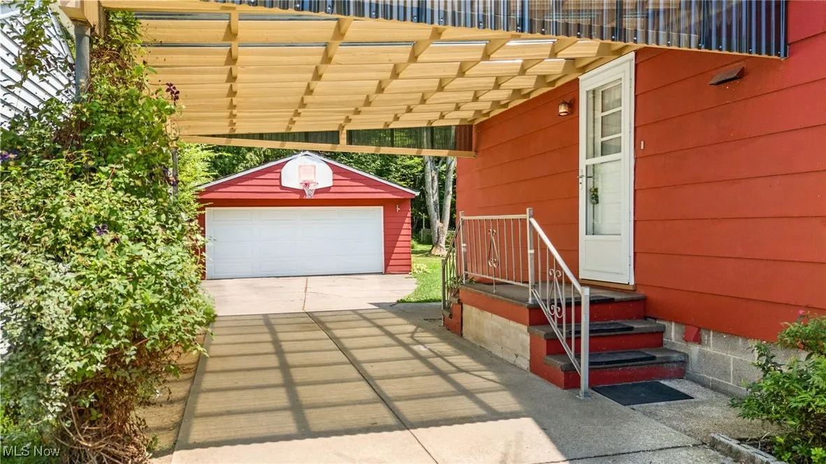 View of patio / terrace with an outdoor structure, concrete driveway, and a detached garage