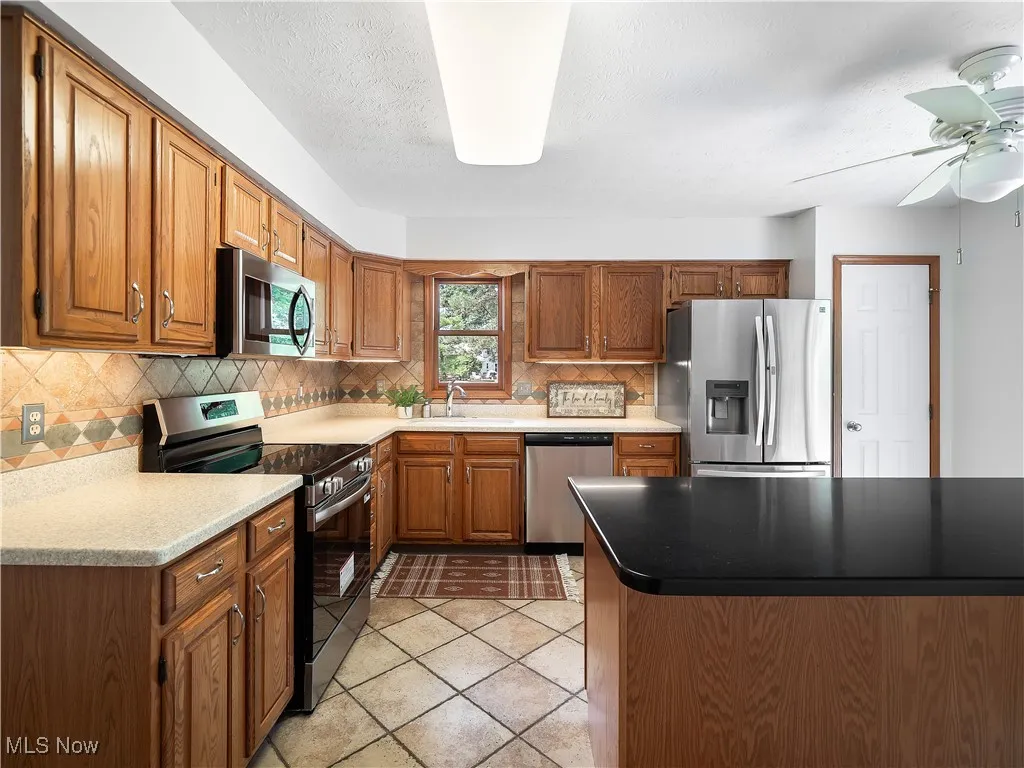 Kitchen with stainless steel appliances, oak cabinets, and island