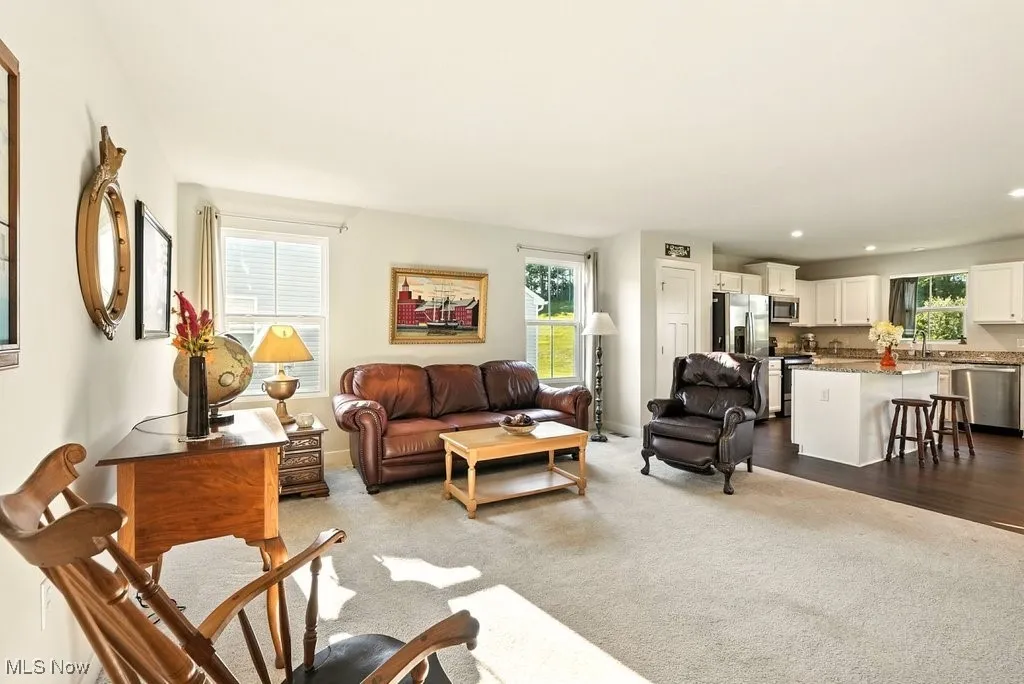 Living area with dark colored carpet and recessed lighting