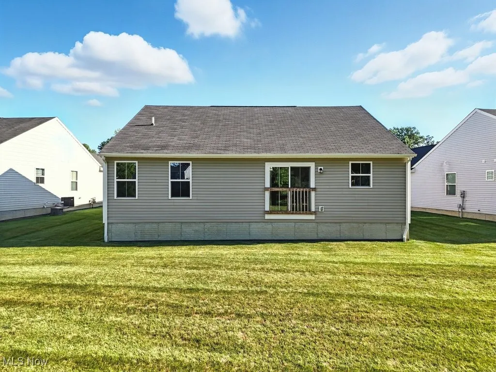 Rear view of house with a yard and a shingled roof