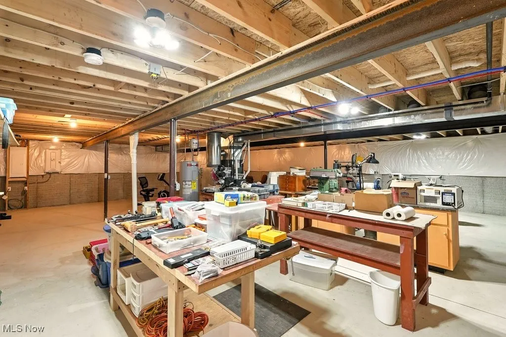 Unfinished basement with electric water heater and a workshop area
