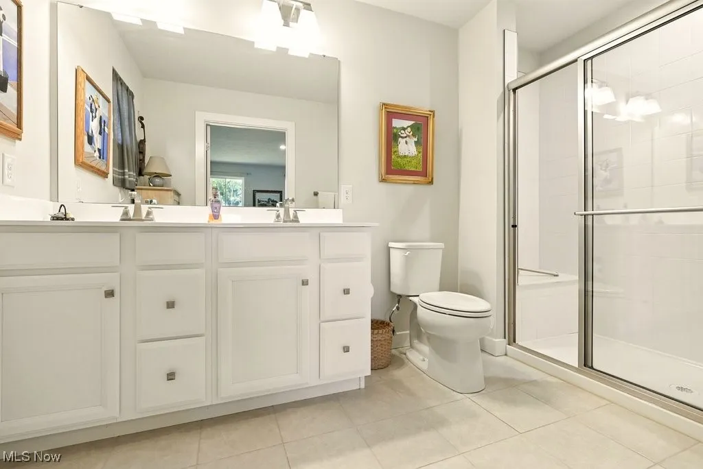 Full bathroom with double vanity, a shower stall, and tile patterned floors