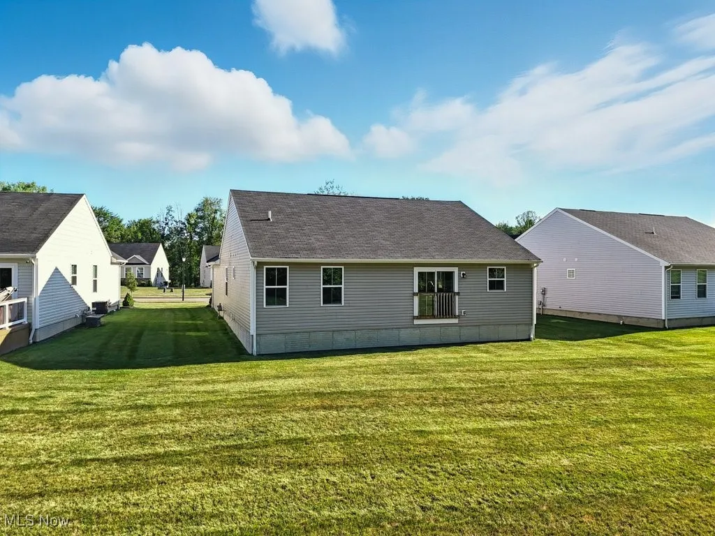 Rear view of house with a shingled roof and a yard