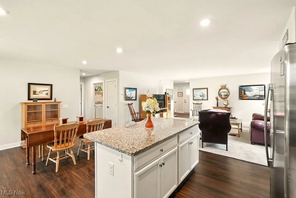 Kitchen with freestanding refrigerator, dark wood-style flooring, a center island, recessed lighting, and light stone counters