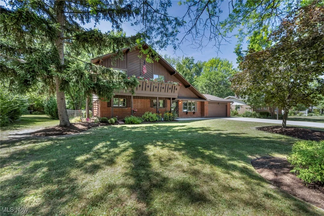 View of front of property with a garage, brick siding, concrete driveway, and a front lawn