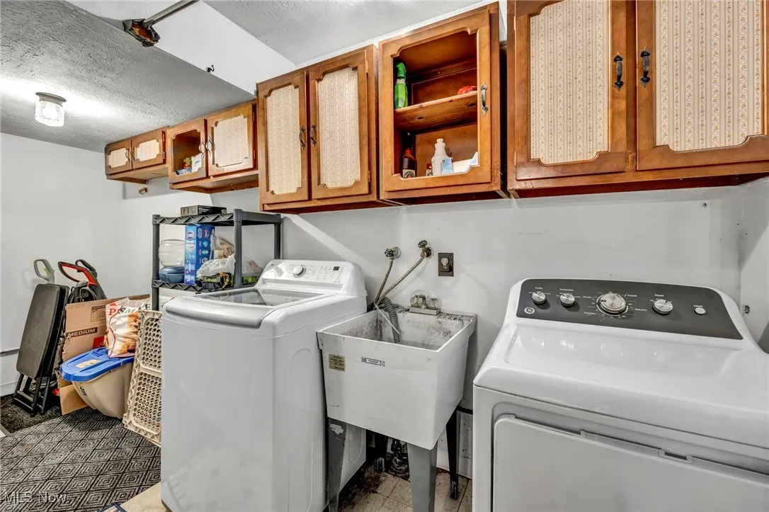 Laundry room featuring cabinet space, separate washer and dryer, and a textured ceiling