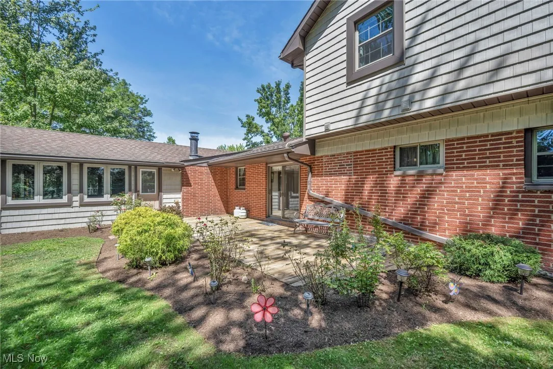 Back of house featuring brick siding, a patio, and a lawn
