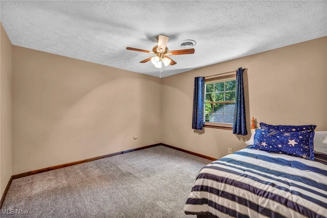 Bedroom featuring carpet floors, a textured ceiling, and a ceiling fan
