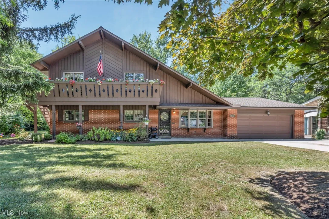 View of front facade with an attached garage, concrete driveway, a front lawn, and brick siding