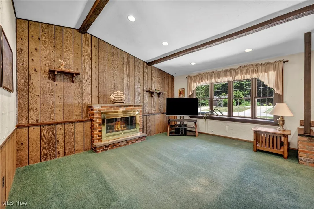 Living area with wood walls, a brick fireplace, carpet floors, and recessed lighting