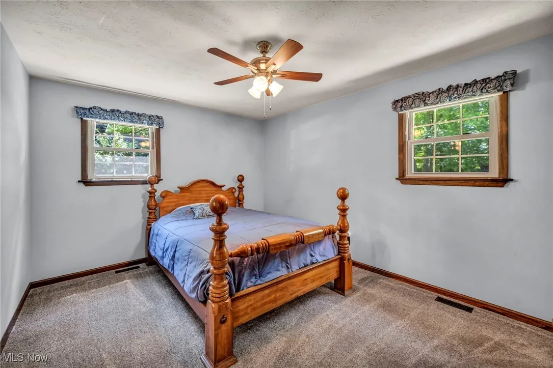 Carpeted bedroom featuring a textured ceiling and ceiling fan