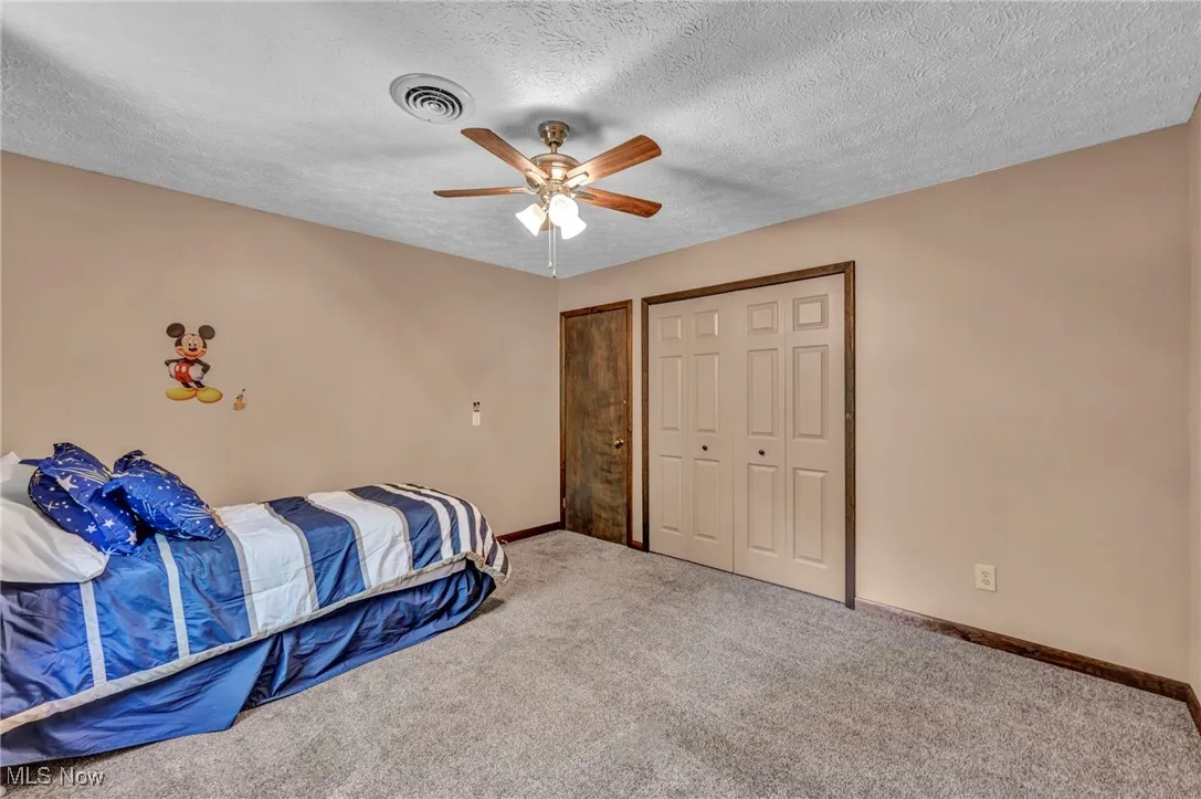 Bedroom featuring carpet, a textured ceiling, a ceiling fan, and two closets