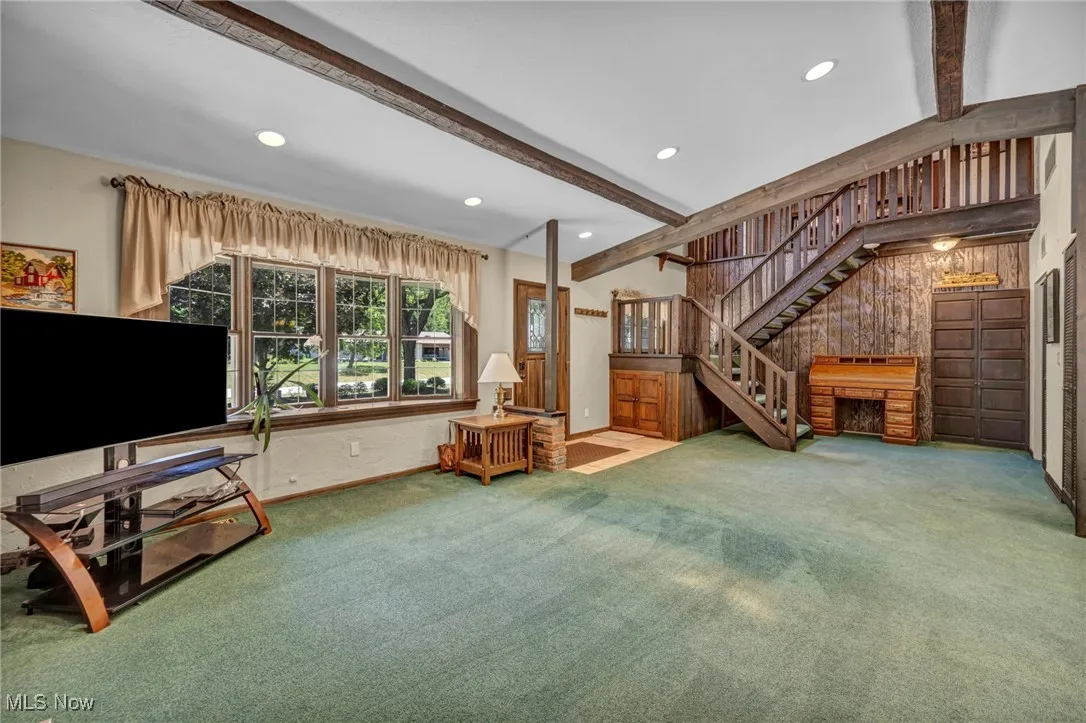 Carpeted living room featuring beamed ceiling, stairway, and recessed lighting