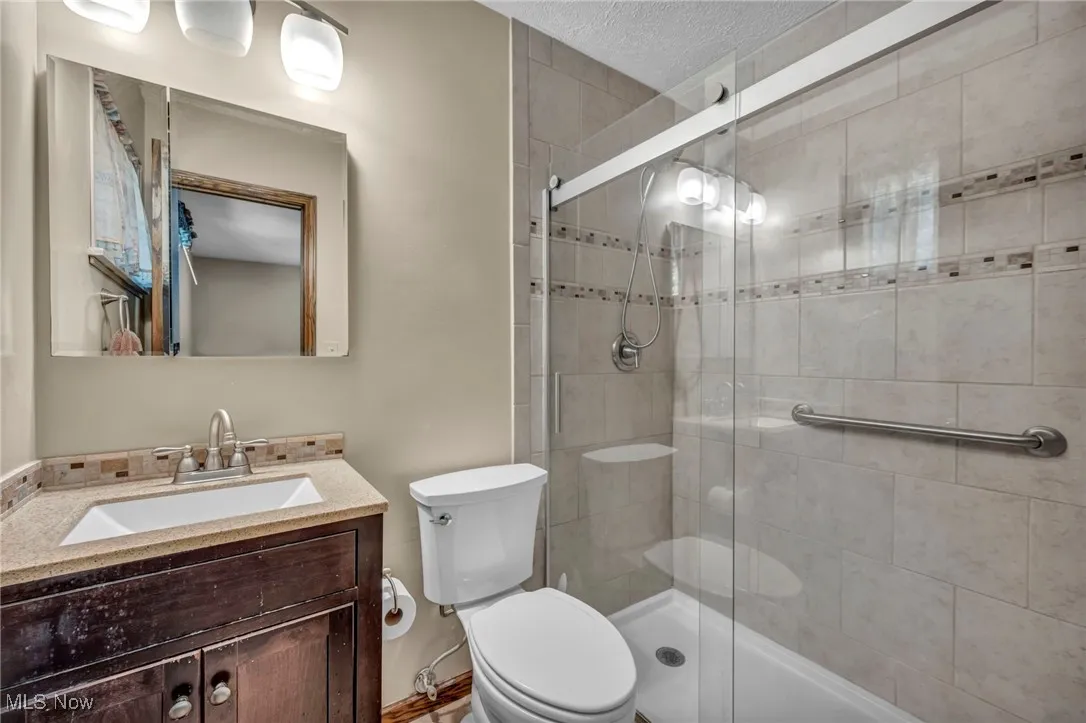 Full bath with a tile shower, vanity, and a textured ceiling