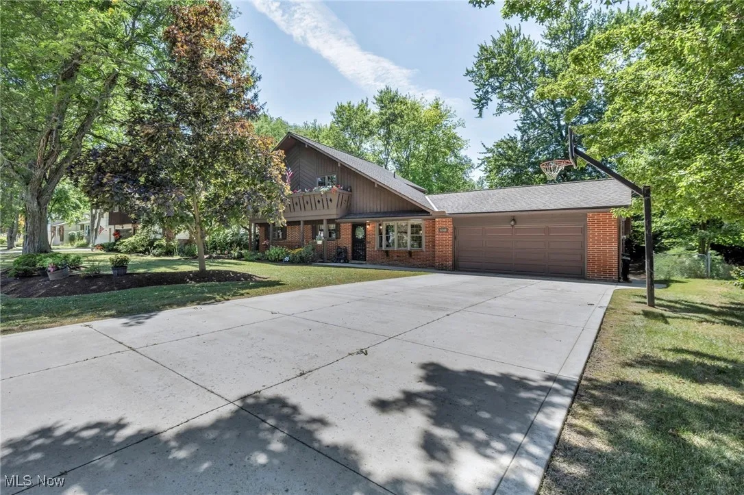 View of front of house with a garage, driveway, a front yard, and brick siding
