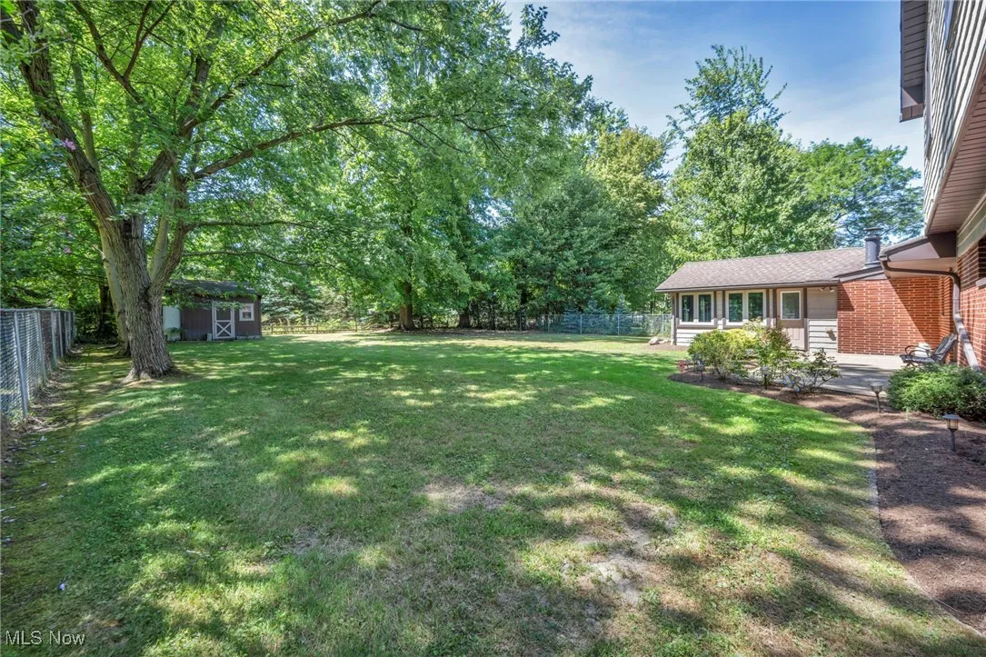 Fenced backyard with a storage shed and view of scattered trees