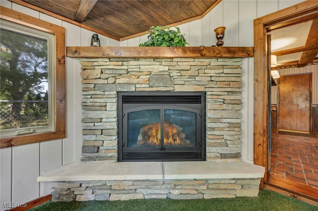 Detailed view of a stone fireplace, a decorative wall, and wooden ceiling