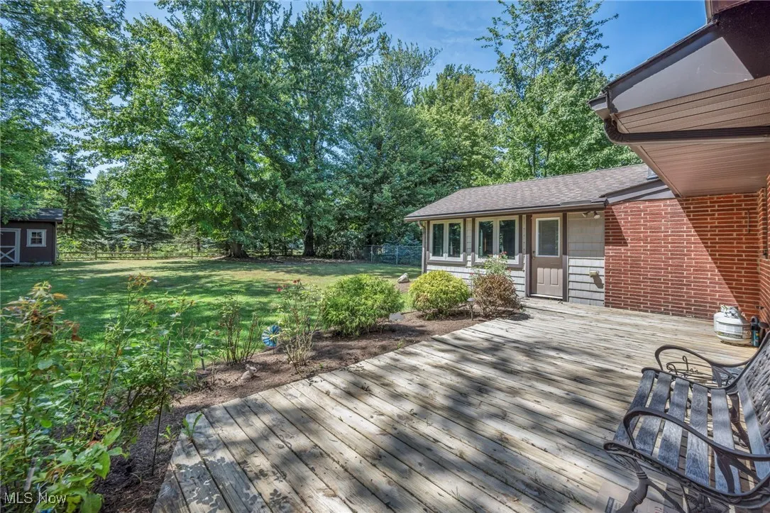 Deck featuring a fenced backyard, a storage shed, and view of scattered trees