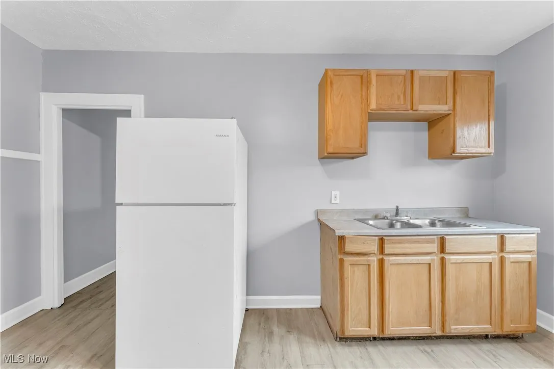 Kitchen featuring freestanding refrigerator, light countertops, light wood finished floors, and light brown cabinets