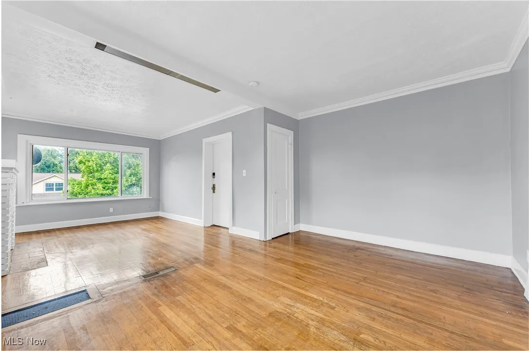 Unfurnished living room featuring crown molding and hardwood / wood-style floors