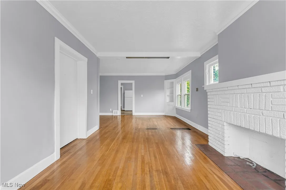 Unfurnished living room with ornamental molding, wood-type flooring, and a fireplace