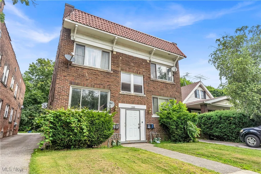 View of front of property with a tile roof, a front yard, and brick siding