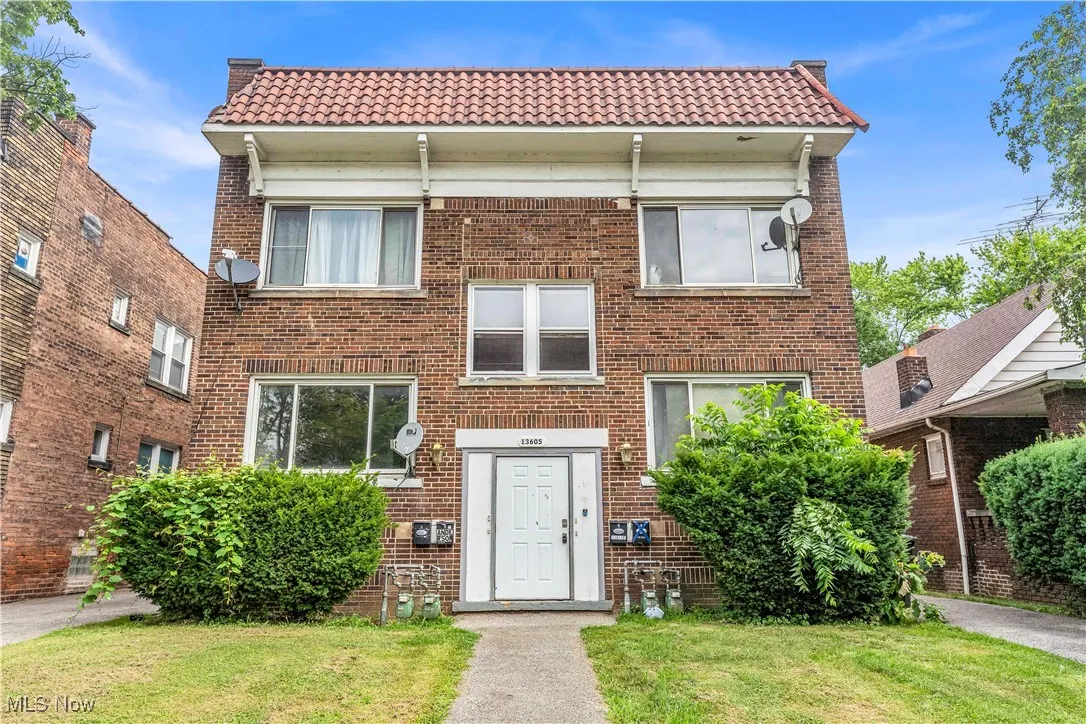 View of front of property featuring brick siding, a front lawn, and a tile roof