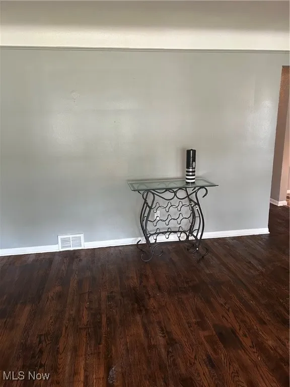 Unfurnished room featuring dark wood-style flooring and baseboards