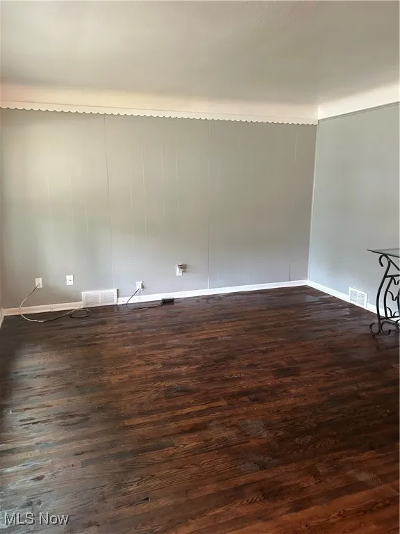 Empty room with dark wood-style flooring and baseboards