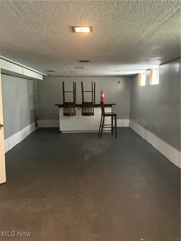 Basement with a textured ceiling and baseboards