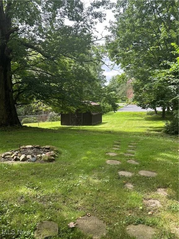 View of yard featuring an outdoor fire pit and an outbuilding