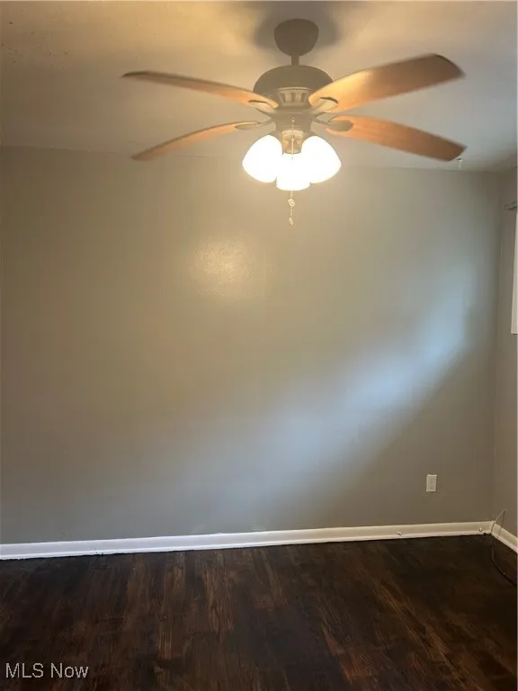 Spare room featuring a ceiling fan and dark wood-style flooring