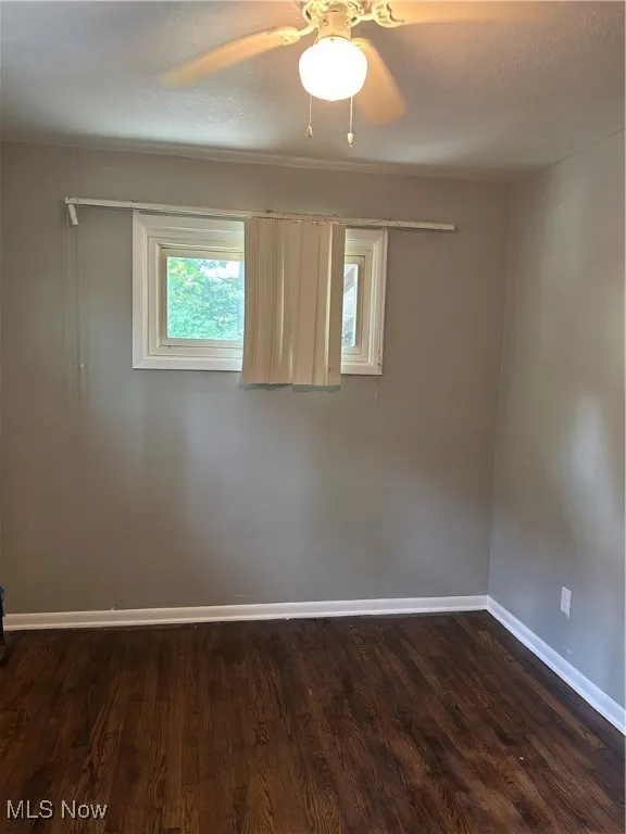 Empty room with dark wood finished floors, a textured ceiling, and ceiling fan