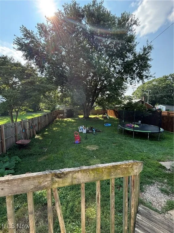 Fenced backyard with a trampoline and a playground