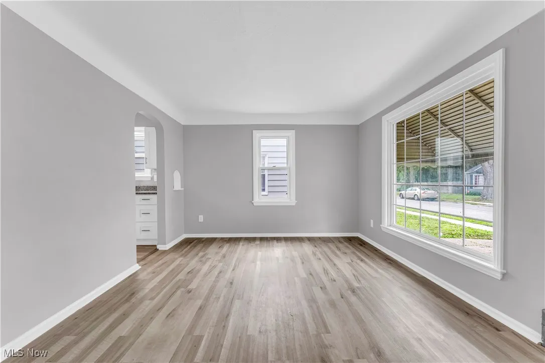 Unfurnished room with light wood-style flooring, healthy amount of natural light, and arched walkways