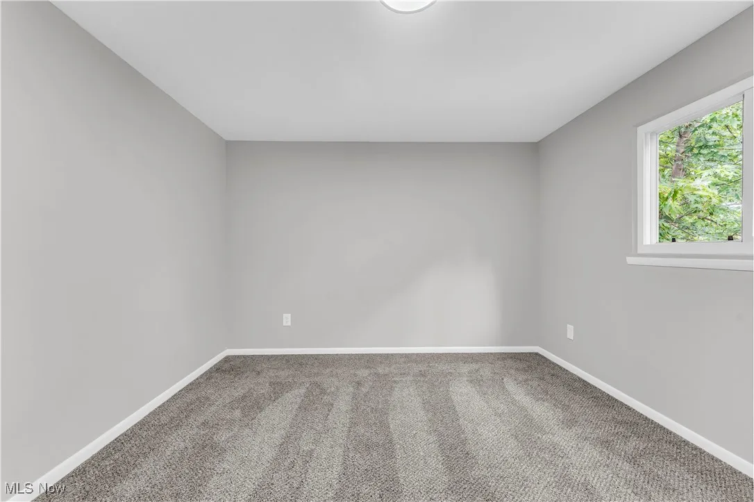 Carpeted spare room featuring baseboards