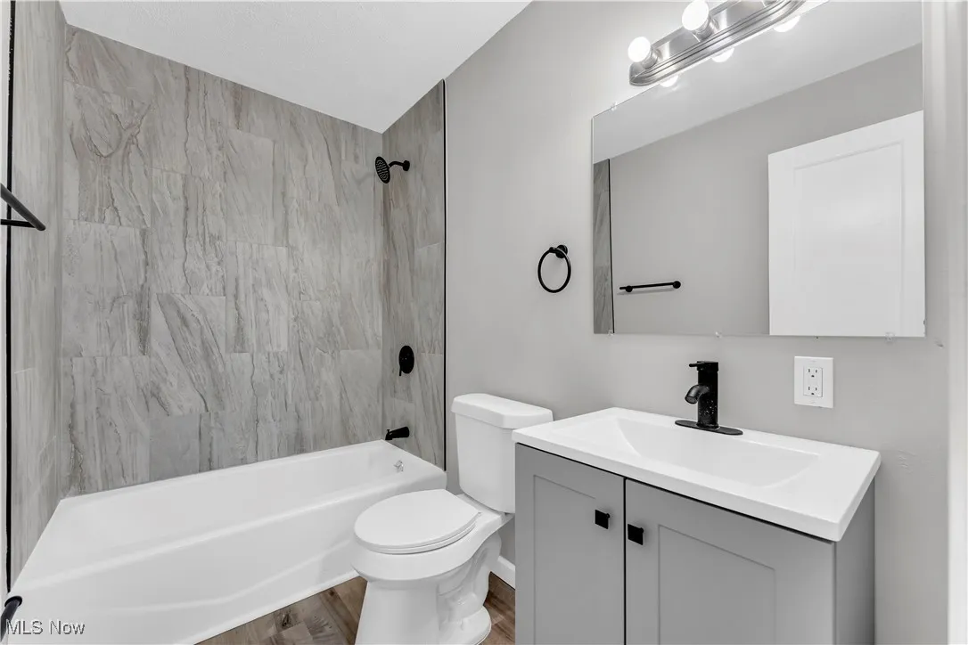 Bathroom featuring vanity, tub / shower combination, and wood finished floors