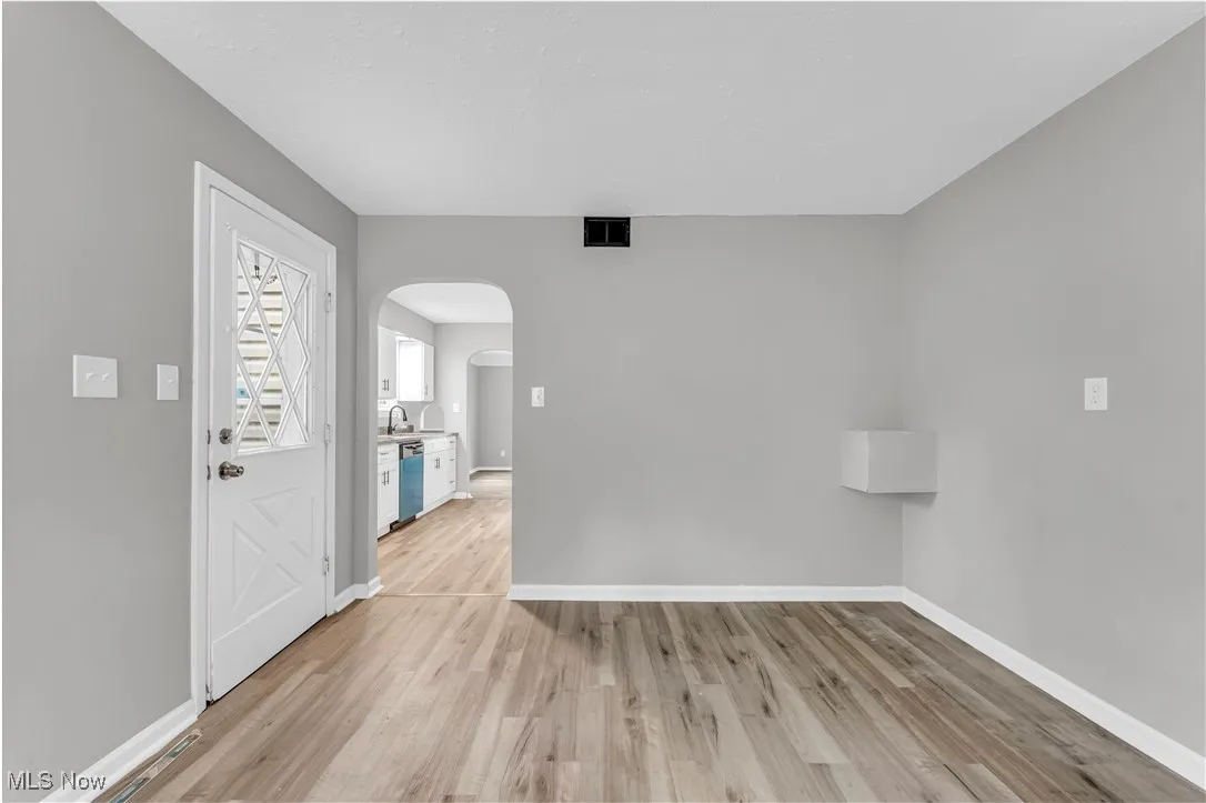 Empty room featuring arched walkways and light wood-type flooring