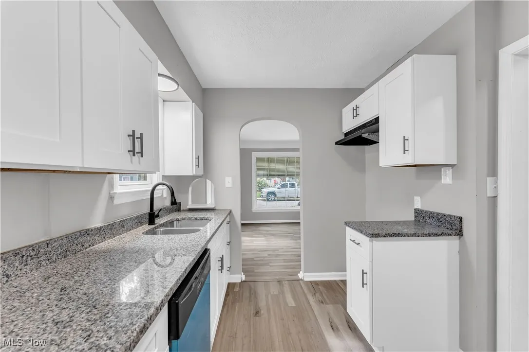 Kitchen featuring light stone counters, light wood finished floors, white cabinets, and a textured ceiling