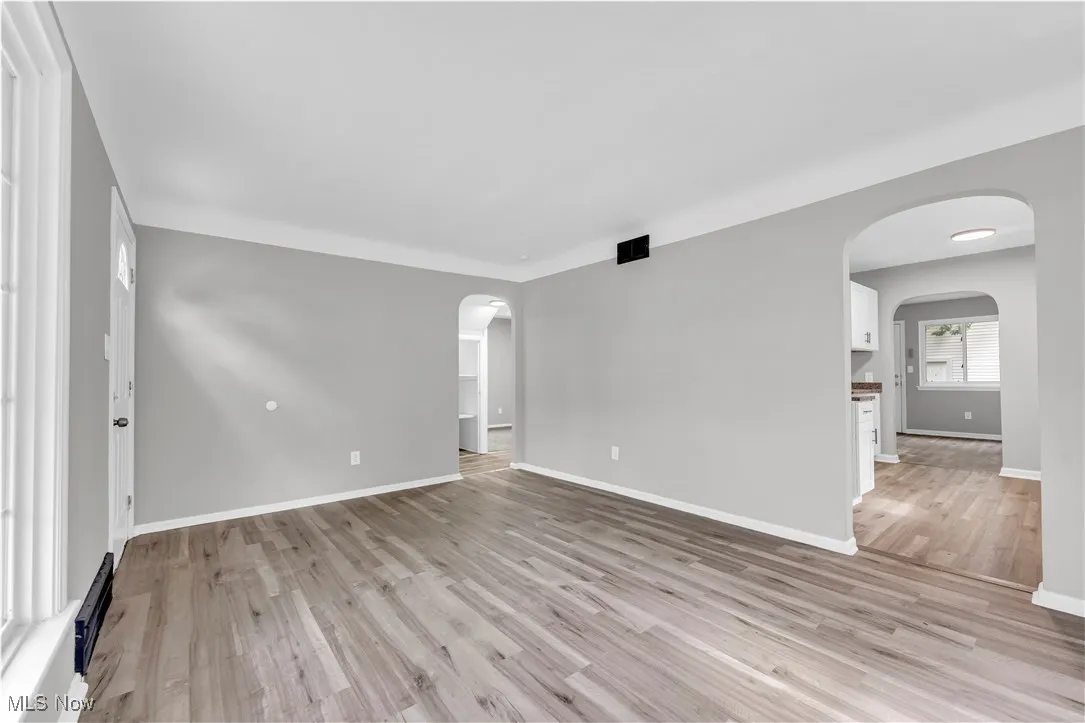 Spare room with arched walkways and light wood-style floors