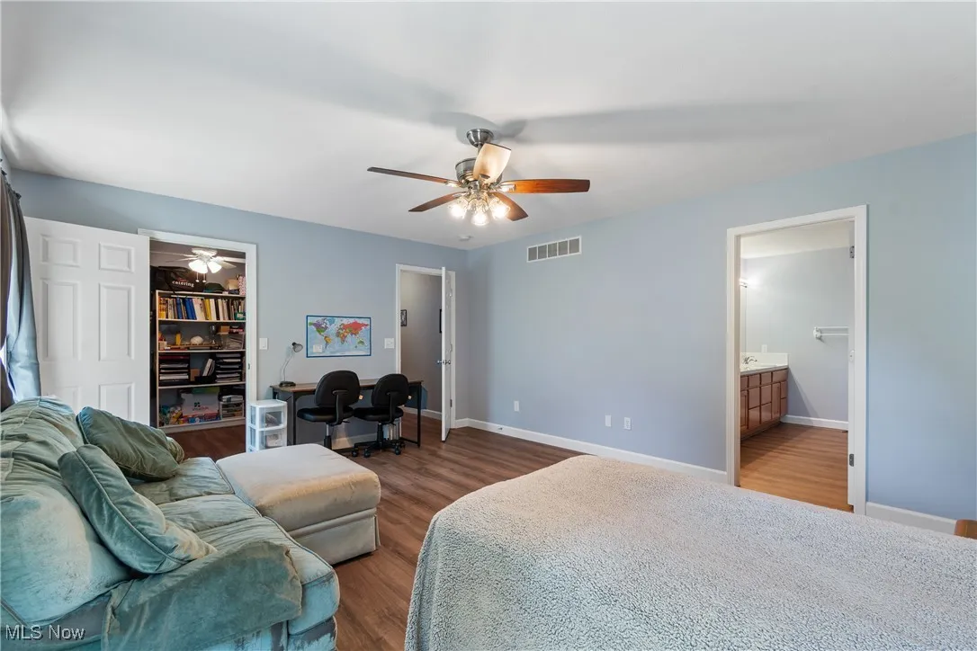 Bedroom with dark wood-style floors, a walk in closet, ceiling fan, and ensuite bathroom