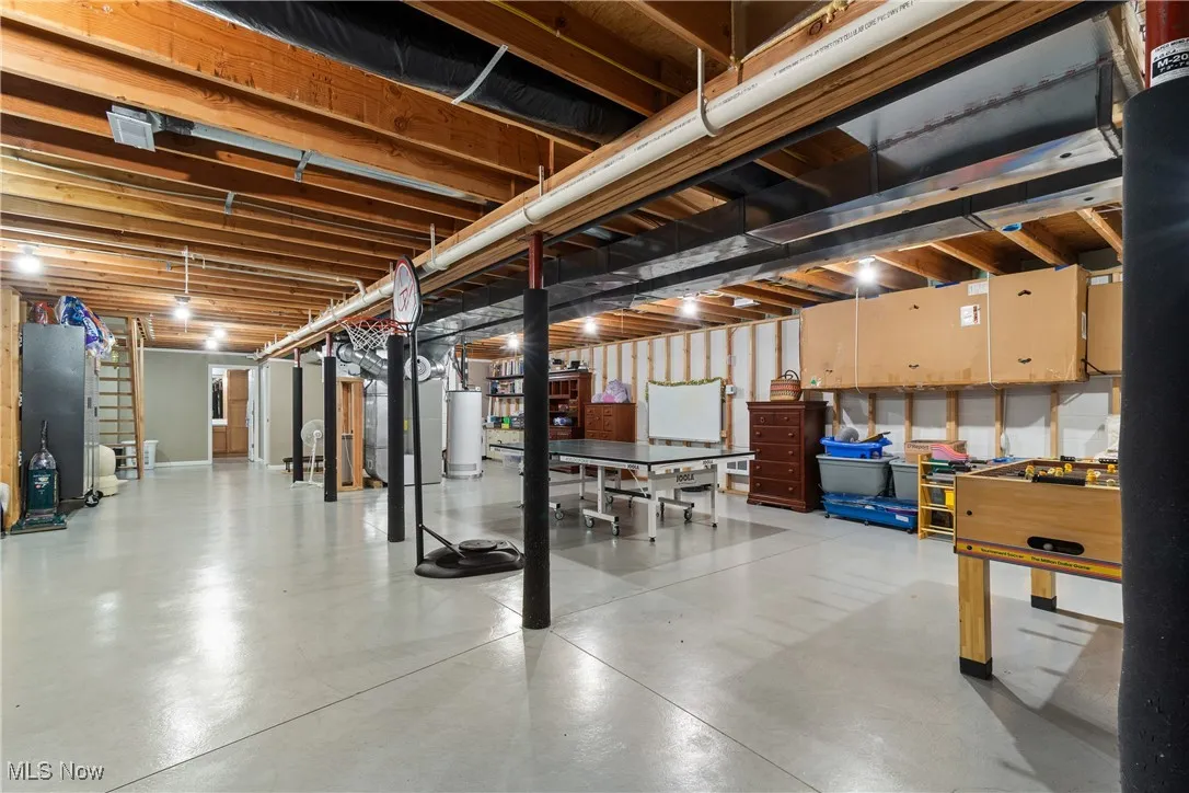 Unfinished below grade area featuring stairway, heating unit, and gas water heater