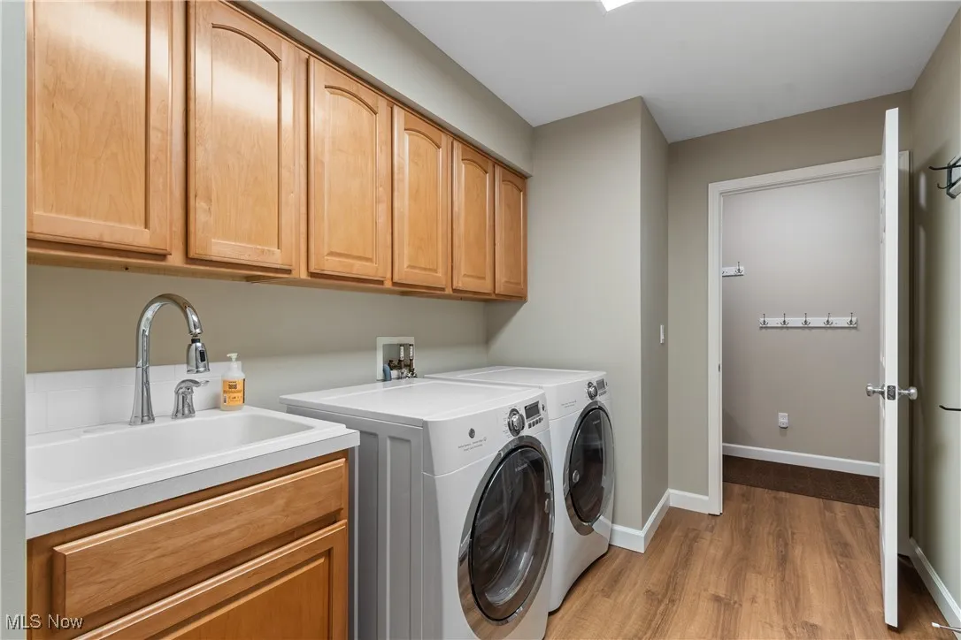 Washroom featuring light wood-style floors, independent washer and dryer, and cabinet space
